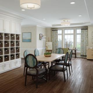 A modern dining room with a large table and upholstered chairs, featuring wooden flooring and ample natural light.