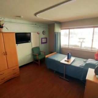 A tidy hospital room with a bed, chair, and window.