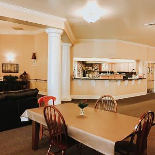 A cozy interior space featuring a dining table with chairs, a sofa in the living area, and an open kitchen.