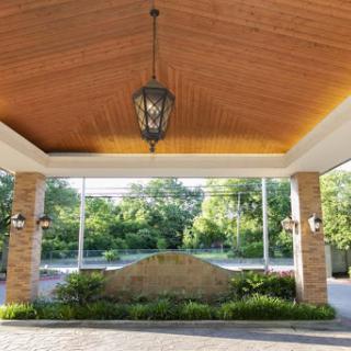A beautifully designed entrance with a wooden ceiling and elegant lighting, surrounded by lush landscaping.
