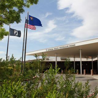 A view of a government building with American and state flags flying in the foreground.