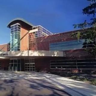A modern building with a combination of glass and brick elements under a clear blue sky.