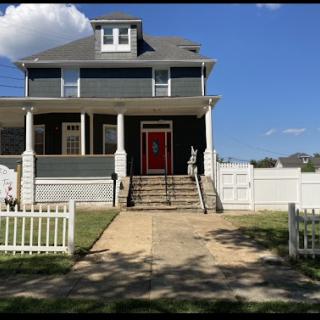 A charming two-story house with a welcoming red door and a landscaped front yard.
