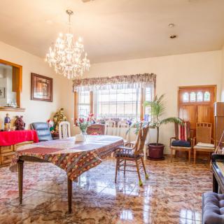 A traditionally decorated dining room with a chandelier and a large table surrounded by chairs.