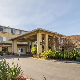 The exterior of a hotel featuring a covered entrance with surrounding greenery.