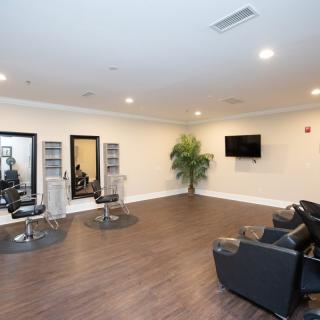 A modern salon interior with chairs, mirrors, and a TV on a wooden floor.