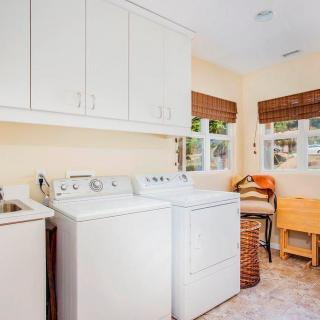 A bright laundry room with a washing machine, dryer, and ample storage space.