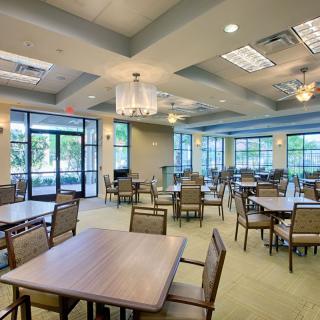 A modern dining area with multiple tables and chairs, featuring large windows and ample lighting.