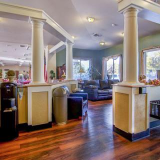 A spacious lobby area with columns, comfortable seating, and wooden floors.