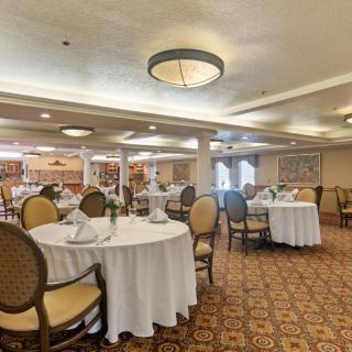 A well-decorated dining area with round tables and elegant chairs, ready for guests.