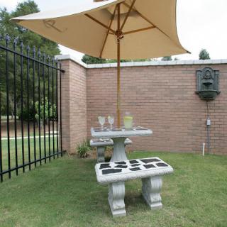 A cozy outdoor seating area with a table, umbrella, and a peaceful garden setting.
