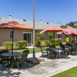 A pleasant outdoor seating area with tables and umbrellas, set in a landscaped garden.