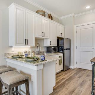 A modern kitchen with white cabinets and a breakfast bar with stools.