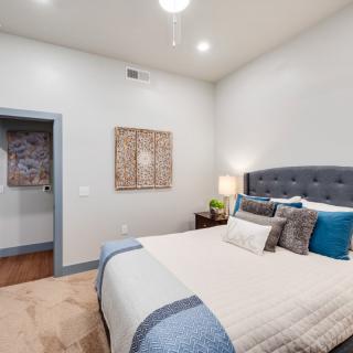 A modern bedroom featuring a cozy bed with decorative pillows, artwork on the wall, and a bedside lamp.