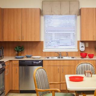 A cozy kitchen setup featuring wood cabinets, a dining table, and modern appliances.