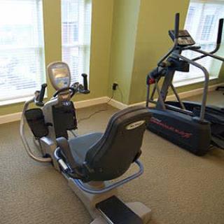 A gym with a recumbent bike and an elliptical machine by the window.