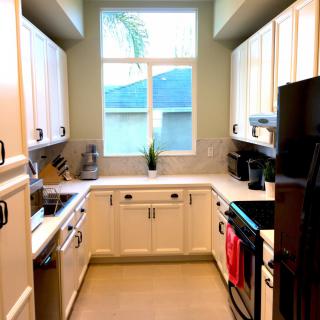 A modern kitchen with white cabinets and a large window.