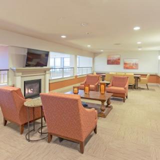 A cozy indoor lounge with comfortable seating, a central fireplace, and a television.