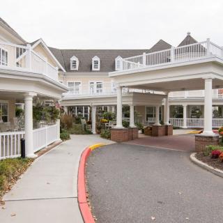 A large residential building with a covered entrance and driveway.