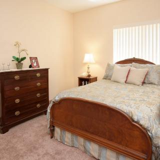 A cozy bedroom with a wooden bed, matching dresser, and soft lighting.