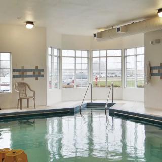 An inviting indoor swimming pool surrounded by large windows letting in natural light.