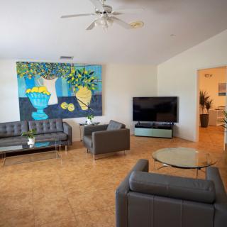 A modern living room featuring sleek gray sofas, a large TV, and vibrant wall art.