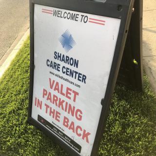 A sign for Sharon Care Center indicating that valet parking is available in the back.