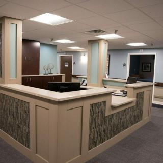 A modern office reception area with a central desk and soft overhead lighting.