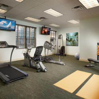 A well-equipped indoor gym space with various fitness machines and televisions.