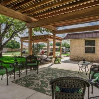 A cozy backyard patio featuring a pergola, comfortable seating, and lush landscaping.