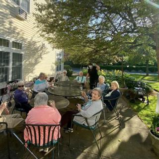 A group of elderly people socializing on a sunny patio.