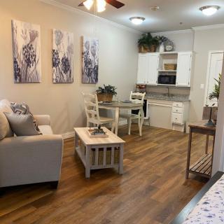 A cozy living area with wooden flooring, featuring a comfortable sofa, a small dining table, and modern kitchen space.