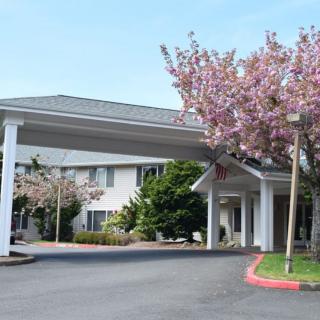 A hotel entrance with a covered driveway surrounded by landscaped trees.