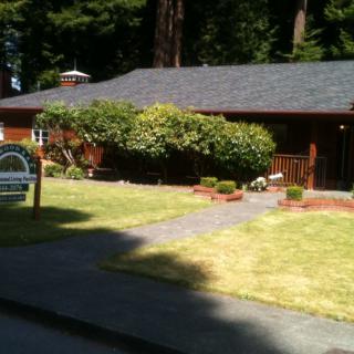 A small residential house with a neatly maintained garden and surrounded by trees.