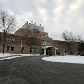 A snow-covered building with a curved driveway leading to its entrance.