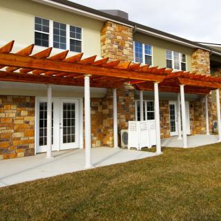 A two-story house with a stone facade and wooden pergola over the patio area.