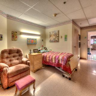 A cozy hospital room with a comfortable chair and a decorated wall.