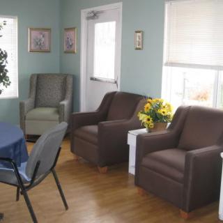 A cozy living room with armchairs, a table, and sunlight coming through the windows.