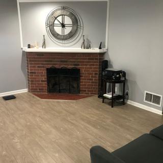 A modern living room features a brick fireplace with a large decorative clock above it.