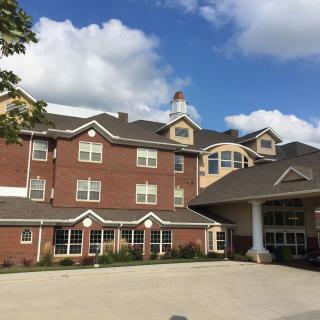 A brick residential building under a blue sky with scattered clouds.