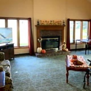A cozy living room with a fireplace, carpeted floor, and comfortable furniture.
