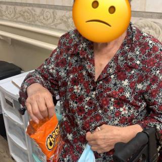 A person sitting in a wheelchair holding a bag of chips indoors.