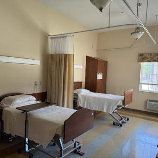 A spacious hospital patient room with two beds and natural light.