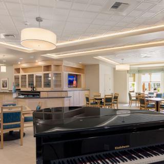 A modern lounge area featuring a grand piano and a bar with ample seating.