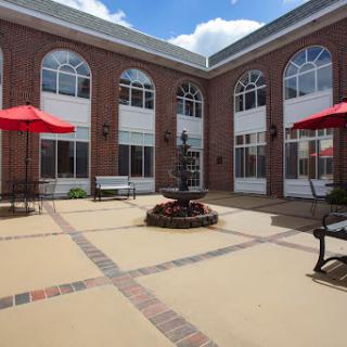 A beautifully designed courtyard with a central fountain surrounded by outdoor seating and red umbrellas.