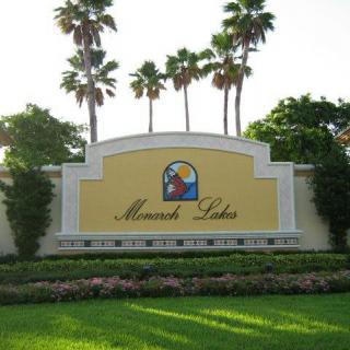 Entrance sign surrounded by palm trees and greenery.