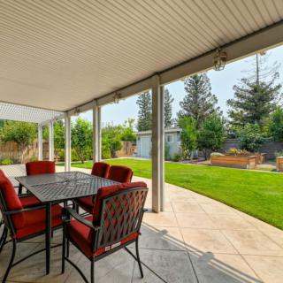 A covered patio with outdoor seating overlooking a well-maintained backyard.