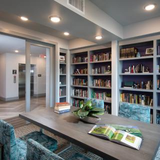 A modern library with teal chairs and bookshelves filled with books.