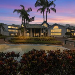 A picturesque view of a resort building at dusk, with palm trees and ambient lighting creating a warm atmosphere.