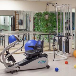 A gym room equipped with various exercise machines and equipment for fitness and rehabilitation.